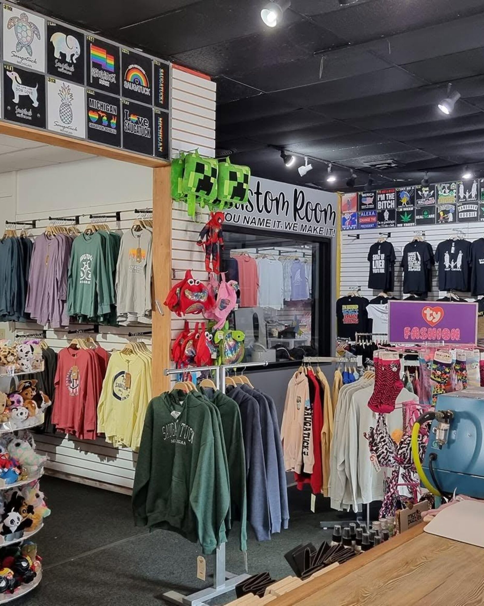 Inside the shop on Butler Street — the Custom Room window, racks of hoodies and sweaters, and the wall of blank tees